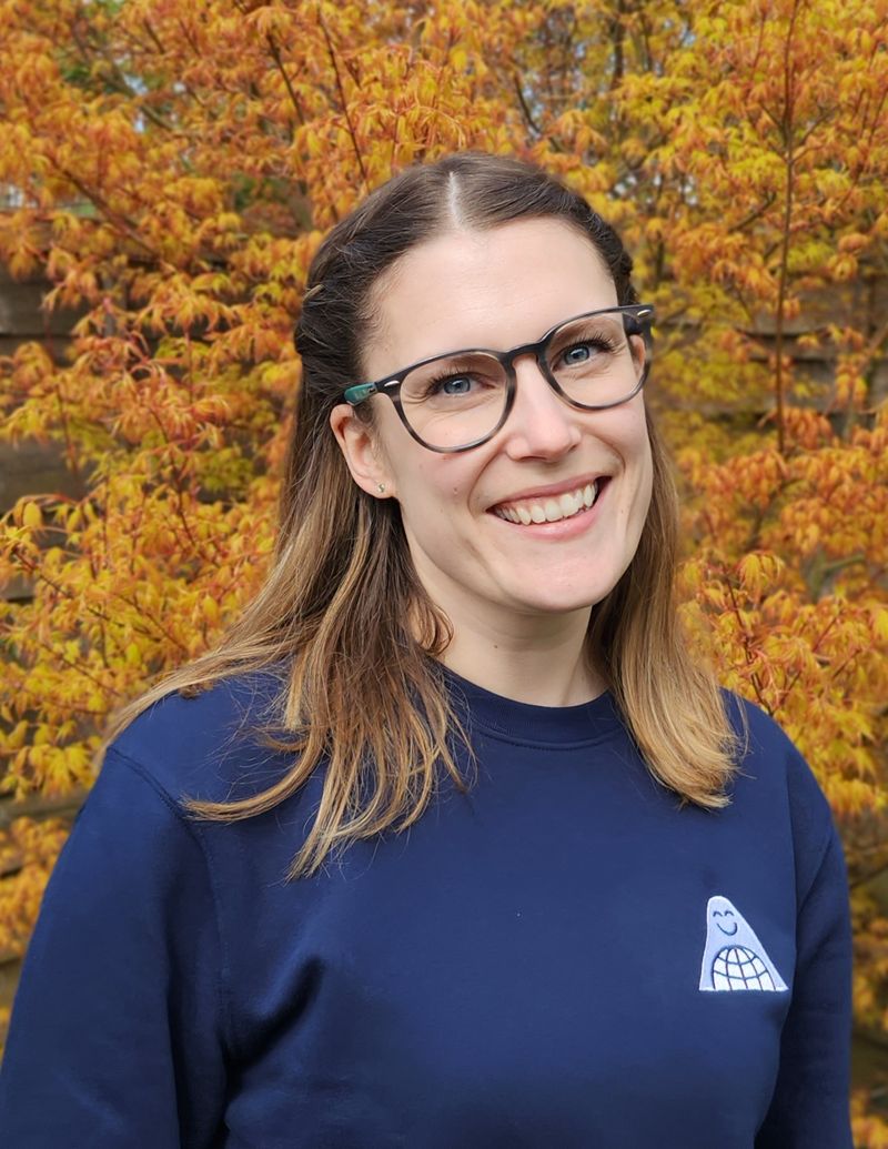 Kayleigh in a navy Sweep jumper in front of an orange acer tree